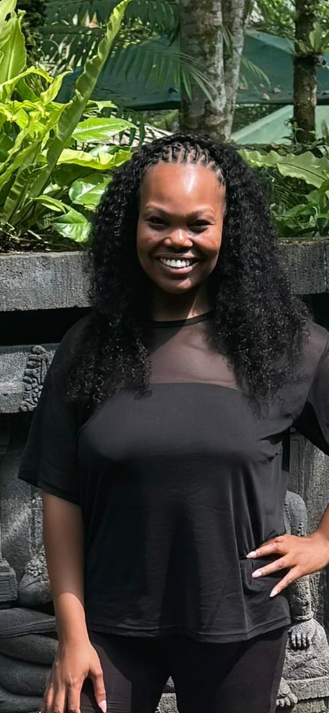 Woman with curly locs black outfit tropical background — natural hair salon Delaware